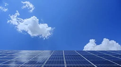 En stor samling av blå solpaneler ses under en klar himmel med några vita moln som reflekterar solljus. Kompositionen betonar förnybar energi och ren teknik, vilket skingra vanliga myter om solenergi med solpanelerna framträdande mot den livfulla blå bakgrunden.